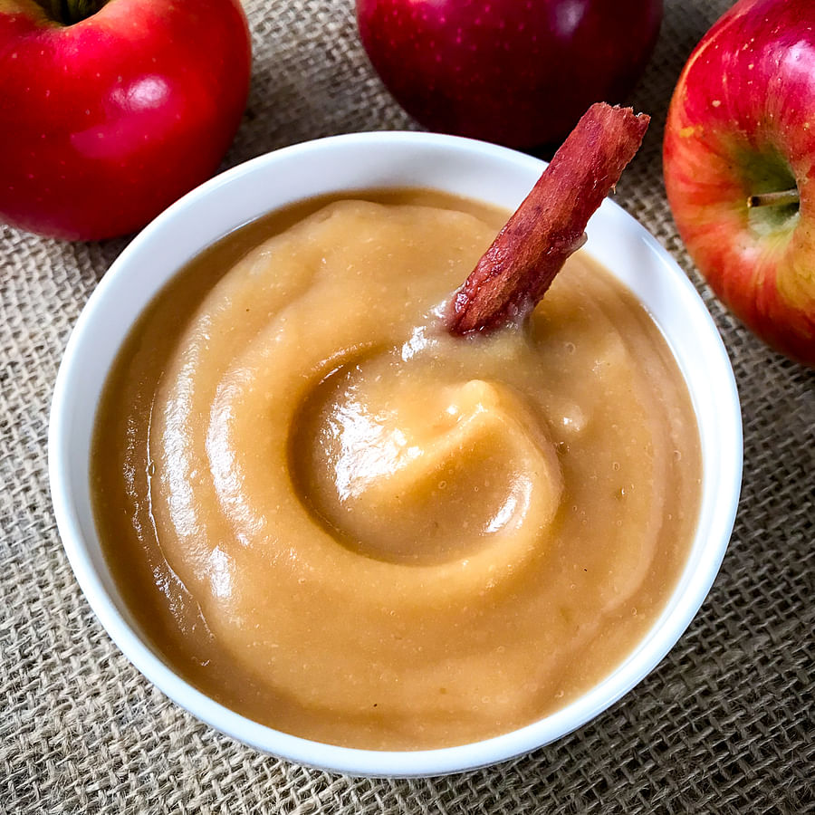 Hand pouring apple sauce into a mixing bowl for gluten-free cake mix